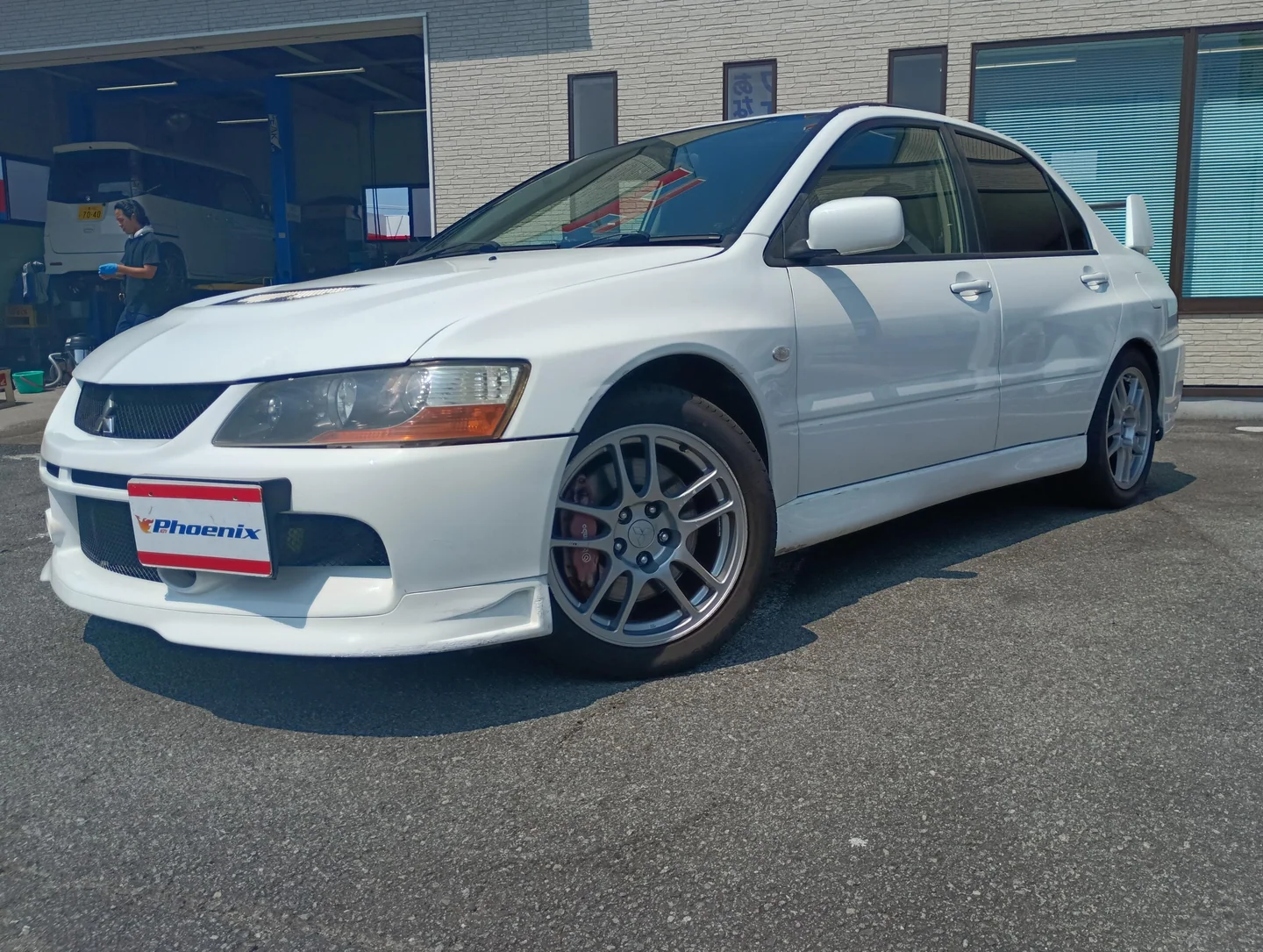 白いMitsubishi Lancer Evolution IX MRの斜め前からの写真。ナンバープレート部分には販売店Phoenixの表示がある。