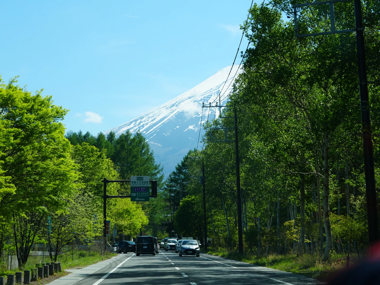 富士スピードウェイへ向かう緑の道の先に、雪を残した富士山がそびえている。